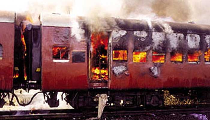 Peringatan: Konten grafis.  Asap mengepul dari gerbong kereta yang terbakar di Godhra, di negara bagian Gujarat, India barat, 27 Februari 2002. Lima puluh sembilan tewas setelah kereta api yang membawa aktivis Hindu dari lokasi kontroversial masjid yang dihancurkan dibakar di barat. India.  — Reuters/Berkas