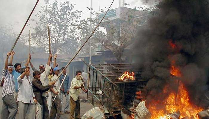 28 فروری 2002 کو مغربی ریاست گجرات کے مرکزی شہر احمد آباد کی سڑکوں پر ایک الاؤ کے پاس کھڑے بھارتی فسادی لاٹھیاں لہرا رہے ہیں۔ — رائٹرز/فائل