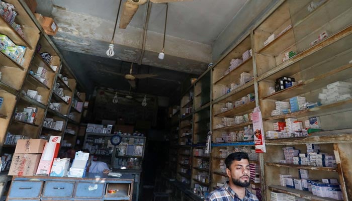 Seorang penjaga toko berbicara dengan seorang pelanggan (tidak ada dalam foto) di sebuah toko medis selama pemadaman listrik di seluruh negeri di Karachi, Pakistan 23 Januari 2023. — Reuters