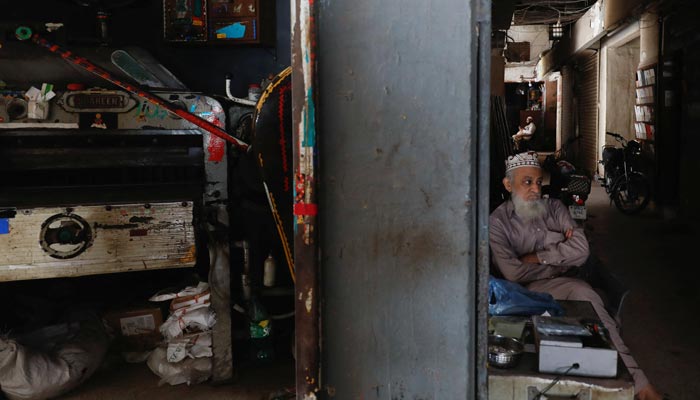 Seorang pria duduk di luar tokonya selama pemadaman listrik di seluruh negeri di Karachi, Pakistan 23 Januari 2023. — Reuters