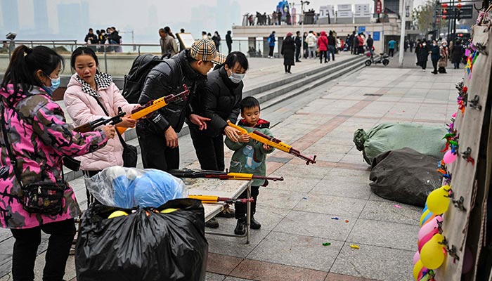 People aim to burst balloons with toy guns at a stall along the Yangtze River in Wuhan, in China´s central Hubei province, on January 22, 2023. — AFP
