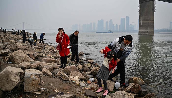 22 جنوری 2023 کو چین کے وسطی صوبہ ہوبی کے ووہان میں دریائے یانگسی کے کنارے لوگ کھڑے ہیں۔ - اے ایف پی