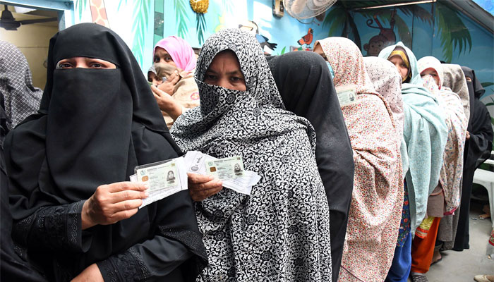 Women voters showing their CNIC cards as stands in a queue outside a polling station to cast their ballots during local government elections, in Karachi. — Online/File