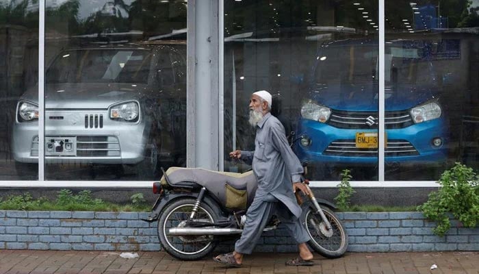 A man walks past a Suzuki outlet, displaying cars in Karachi, Pakistan, July 27, 2022. — Reuters/File