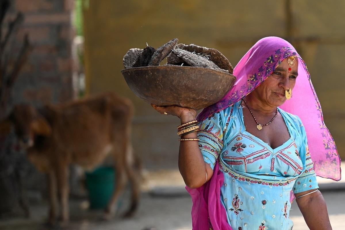 ایک عورت ایندھن کے طور پر استعمال ہونے کے لیے گائے کا گوبر لے جاتی ہے۔— اے ایف پی/فائل