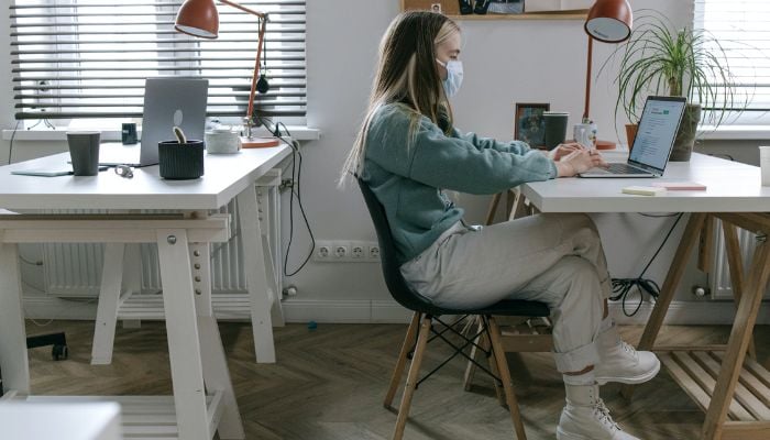 Woman Using a Laptop on a White Desk in an Office.— Pexels