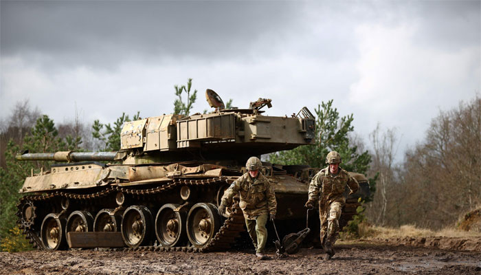 Ukrainian soldiers carry a snatch block back to their recovery vehicle after winching a stricken battle tank from a waterlogged ditch and up a hill during the Royal Electrical & Mechanical Engineering Exercise called Iron Challenge at the Longmoor training area, near Bordon, Hampshire. — AFP/File