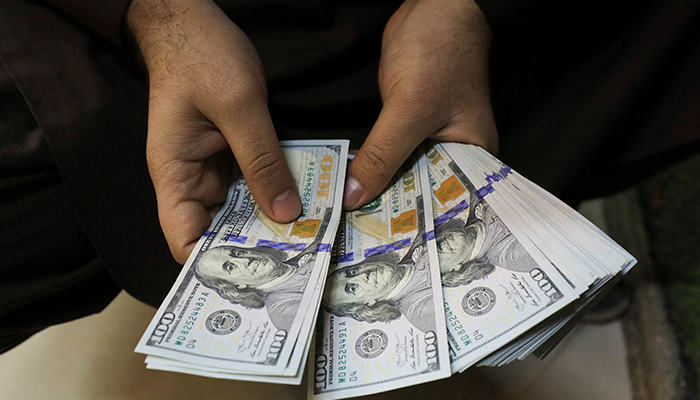 A trader counts US dollar banknotes at a currency exchange booth in Peshawar, Pakistan January 25, 2023. — Reuters