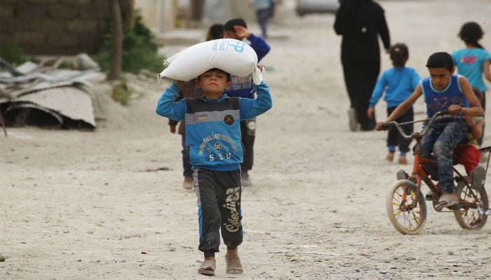 A boy carries food aid given by the UNs World Food Programme in Raqqa, Syria. — Reuters/File