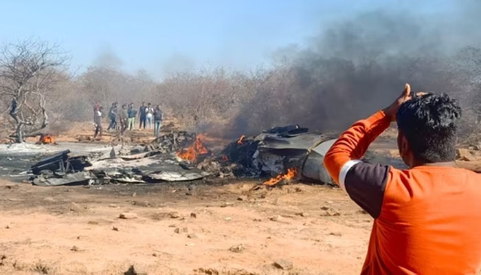 A man watches the burning debris of the downed jets at the site of crash. — Hindustan Times
