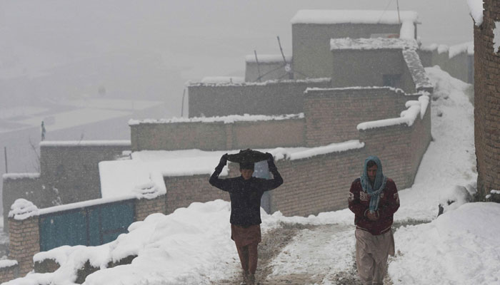 In this file photo taken on January 11, 2023, men walk along a street during snowfall in Kabul. — AFP