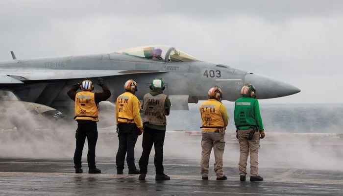 Crew members signal to a F/A-18E Super Hornet fighter jet preparing to take off for a routine flight on board the US USS Nimitz aircraft carrier during a routine deployment to the South China Sea, Mid-Sea, January 27, 2023. — Reuters