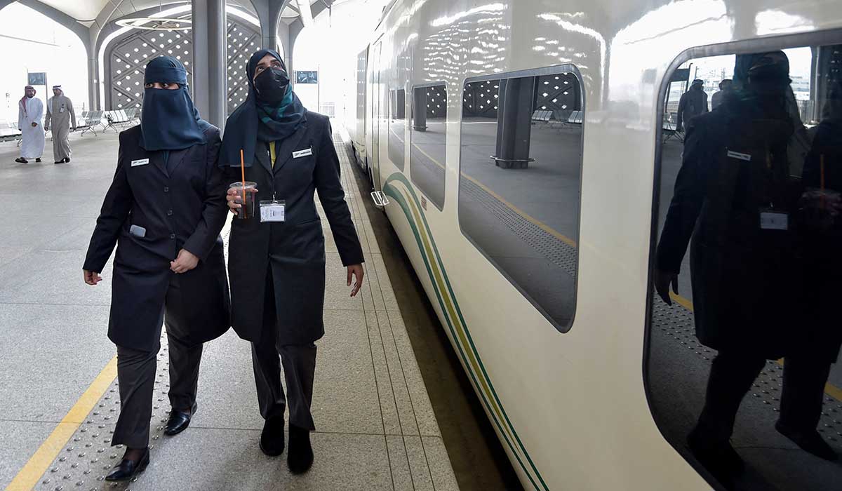 Conductors walk beside a high-speed train ferrying pilgrims to Makkah. — AFP