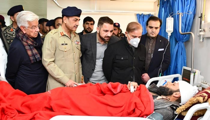 وزیر اعظم شہباز شریف 30 جنوری 2023 کو لیڈی ریڈنگ ہسپتال میں ایک متاثرہ کو تسلی دے رہے ہیں، ان کے ہمراہ سی او اے ایس جنرل عاصم منیر اور کابینہ کے اراکین۔ — Twitter/@WorldPTV