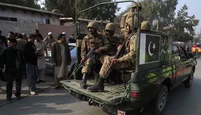 16 دسمبر 2014 کو پشاور میں آرمی پبلک اسکول کی طرف جانے والی سڑک پر سیکیورٹی فورسز گاڑی چلا رہی ہیں۔ — رائٹرز
