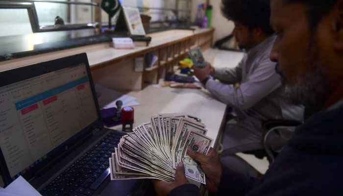 A dealer counts US dollars at a money exchange market in Karachi on January 26, 2023. — AFP/File