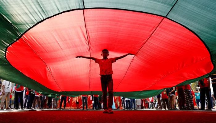 A boy poses for a picture under a massive Bangladeshi flag, during a flag rally three days ahead of the countrys 50th Victory Day anniversary, in front of the parliamentary building in Dhaka, Bangladesh, December 13, 2021.— Reuters