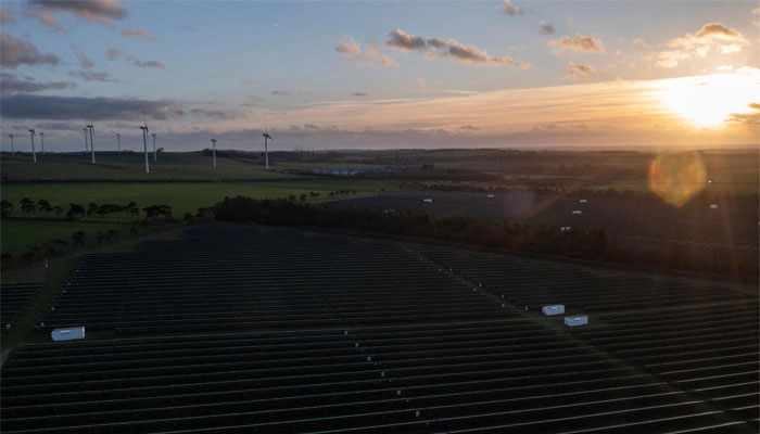 An aerial view shows wind turbines in the countryside, and the photovoltaic (PV) solar panels making up the Great Wilbraham Solar Park, near Fulbourn, east of Cambridge in Eastern England. — AFP/File