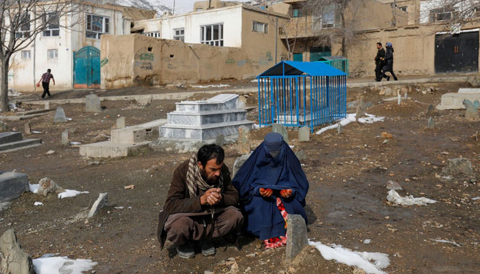 The parents of Amrullah, a child who died due to cold, pray at his grave in Kabul, Afghanistan, January 31, 2023. REUTERS