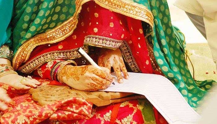 A bride signs a marriage certificate. — AFP/File