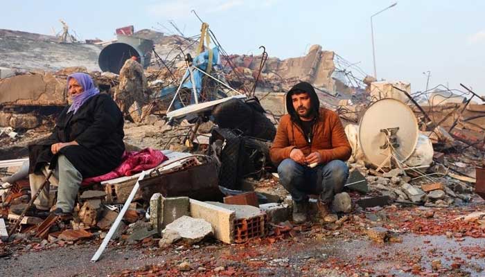 People sit amid rubble following an earthquake in Hatay, Turkey, February 7, 2023. — Reuters
