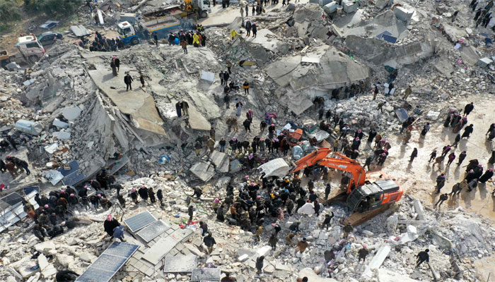 This aerial view shows residents searching for victims and survivors in the village of Besnia near the twon of Harim, in Syria, on the border with Turkey, on February 6, 2022. — AFP