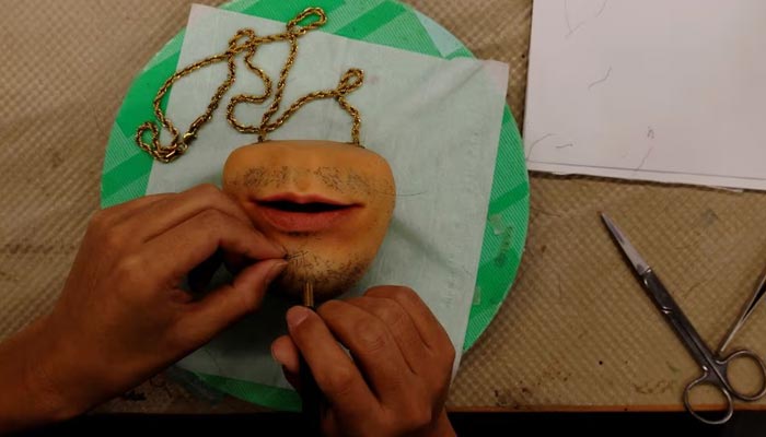 A staff of Amazing studio JUR, plants hair on a coin purse shaped like a humans mouth, created by Masataka Shishido, also known as DJ Doooo, during its production at the studio in Tokyo, Japan February 2, 2023. — Reuters
