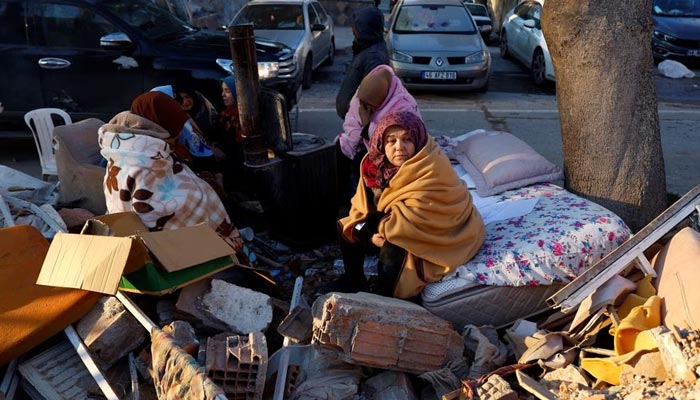 People sit next to rubble at the site of a collapsed building following an earthquake in Kahramanmaras, Turkey, February 8, 2023. — Reuters