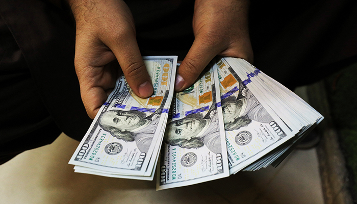 A trader counts US dollar banknotes at a currency exchange booth in Peshawar, on January 25, 2023. — Reuters