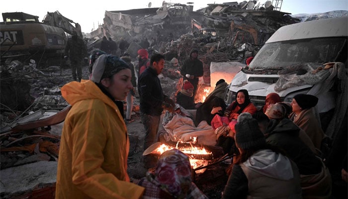People sit near a bonfire amidst the rubble of collapsed buildings in Kahramanmaras, on February 8, 2023, two days after a 7,8-magnitude earthquake struck southeast Turkey. — AFP.