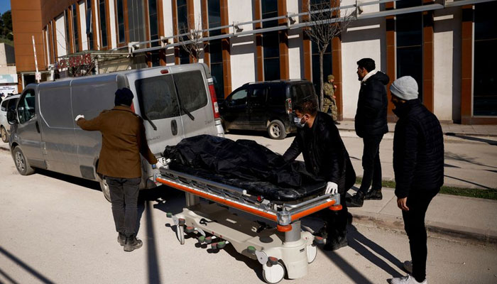 People stand next to a trolley bed with the body of a victim outside a hospital, in the aftermath of a deadly earthquake, in Kirikhan, Turkey February 9, 2023.— Reuters