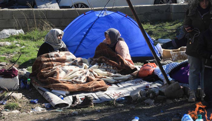 Two women sit next to a tent in Nurdagi, in the countryside of Gaziantep, on February 9, 2023, three days after a deadly earthquake that hit Turkey and Syria. — AFP