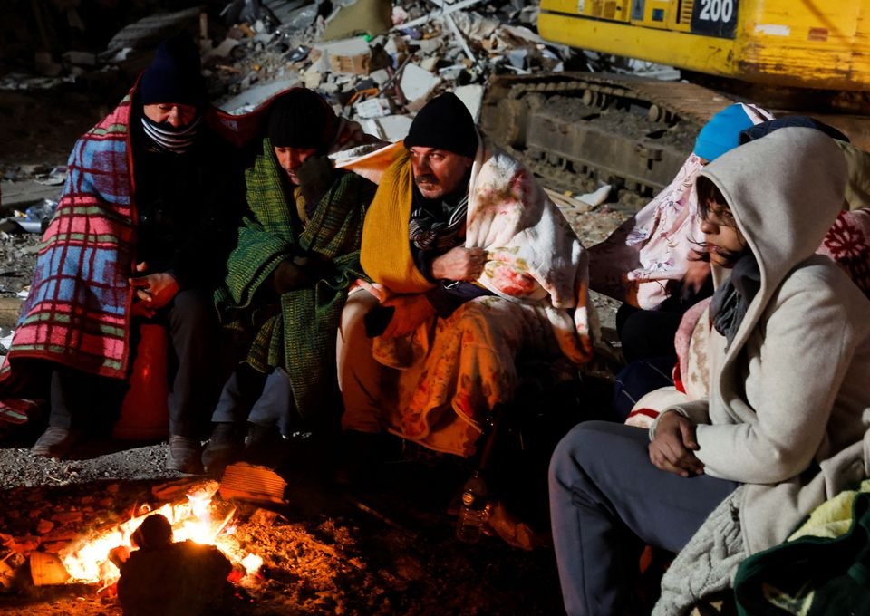 Zubeyde Kahraman (R), whose sister Zeynep, 40, is being rescued by ISAR Germany, waits by a fire with her family during the rescue operation that ISAR Germany say has taken almost 50 hours, as the search for survivors continues, in the aftermath of a deadly earthquake in Kirikhan, Turkey February 10, 2023.— Reuters