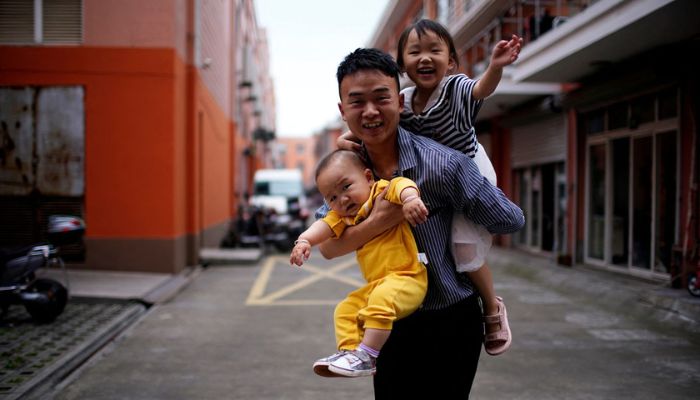 A father plays with his two children on the outskirts of Shanghai, China June 3, 2021.— Reuters