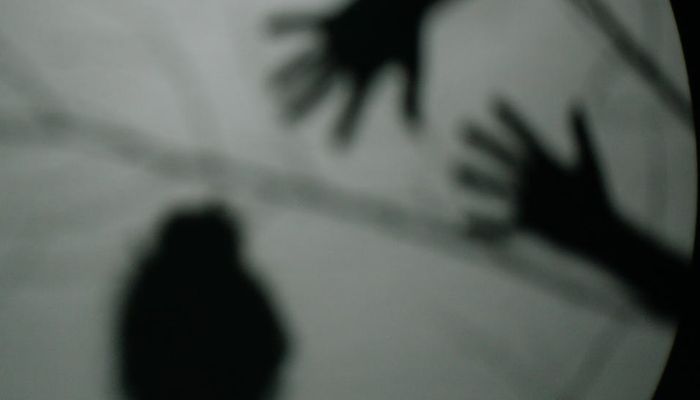 Image shows shadowy hands hovering over the shadow of a person. Pexels