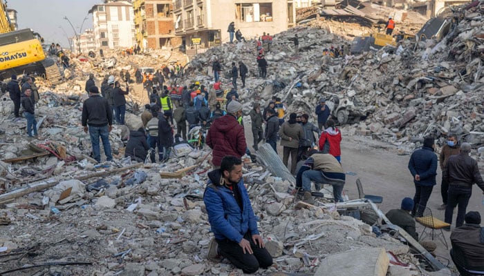 A man kneels on the rubble of a collapsed building during rescue operations in Hatay on February 12, 2023. —AFP