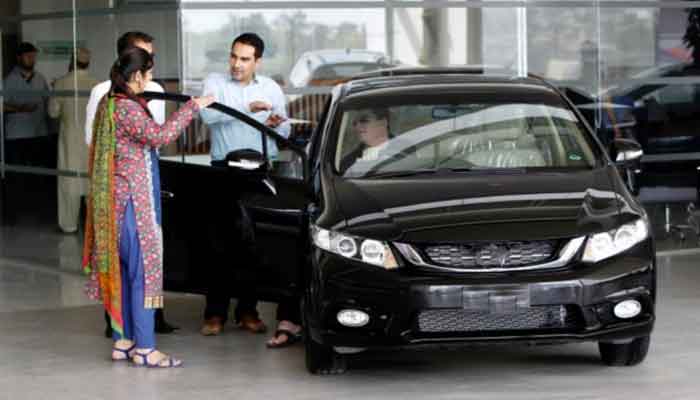 A customer speaks with salespeople at a car dealership in Rawalpindi, Pakistan.  Reuters/File