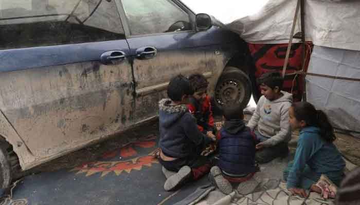 Children sit together next to Abdelrahman Ghilans car with a tented extension, after his house was partially collapsed in the earthquake, in rebel-held town of Jandaris, Syria February 13, 2023.— Reuters