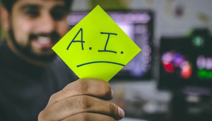 A man holds a sticky note that reads A.I.— Unsplash