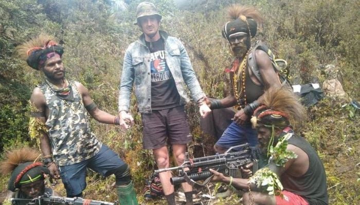 A man, identified as Philip Mehrtens, the New Zealand pilot who is said to be held hostage by a pro-independence group, stands among the separatist fighters in Indonesias Papua region, in this undated picture released on February 14, 2023.— Reuters