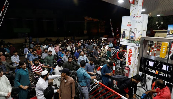 People wait for their turn to get petrol at a fuel station in Karachi on November 24, 2021. — Reuters