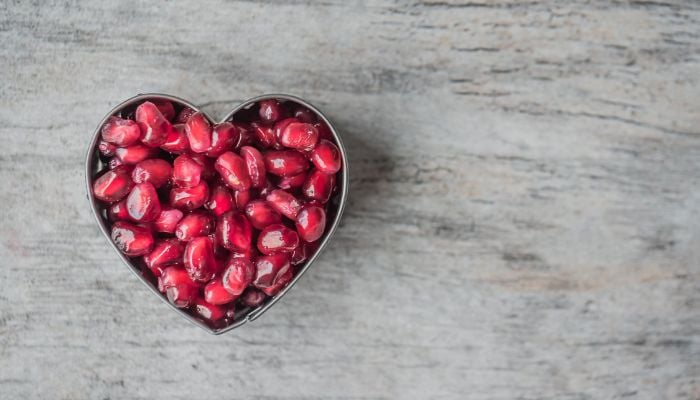 Silver heart bowl filled with red pomegranate seeds.— Pexels