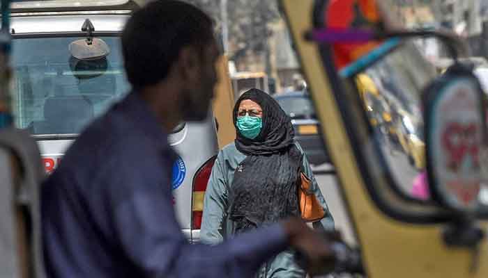 A woman crosses a road in Karachi on March 13, 2020. — AFP