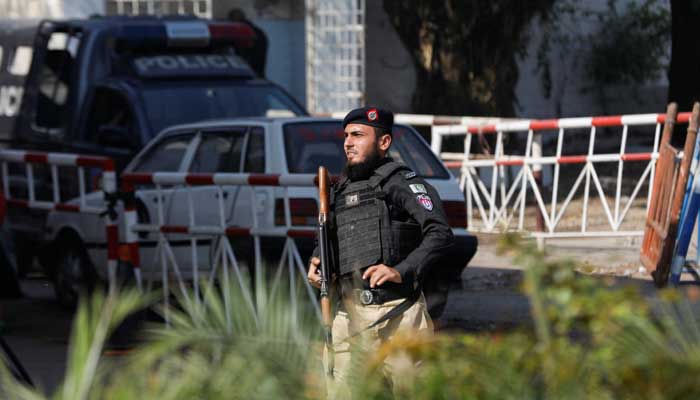 18 فروری 2023 کو کراچی میں ایک پولیس اسٹیشن پر حملے کے بعد ایک پولیس افسر عمارت کی طرف جانے والے راستے کی حفاظت کر رہا ہے۔ — رائٹرز