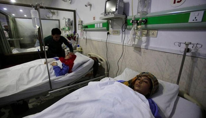Seorang kerabat merawat wanita di rumah sakit CMH di Sialkot, Pakistan.  — Reuters/Berkas