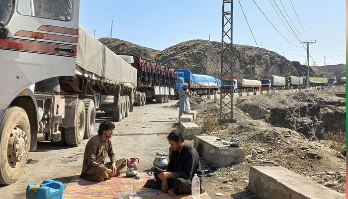 Men sit near a queue of trucks loaded with supplies to leave for Afghanistan, after Taliban authorities have closed the main border crossing in Torkham, Pakistan February 21, 2023. — Reuters