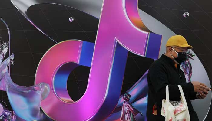 A man stands near a giant sign of Chinese company ByteDances app TikTok, known locally as Douyin, during China Fashion Week, in Beijing, China March 31, 2021. — Reuters