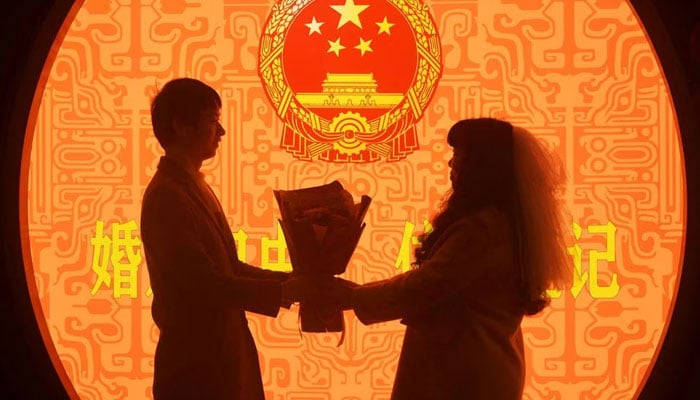 A newly wed couple pose for pictures on Valentines Day at a marriage registration office in Hangzhou, Zhejiang province, China February 14, 2023. Reuters