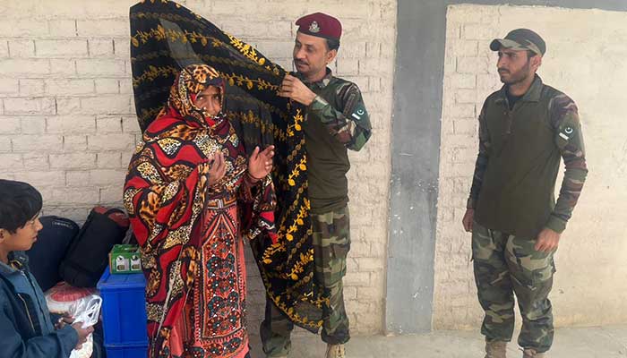 Giran Naz and her children are seen walking with the Levies personnel after being rescued. — Geo News