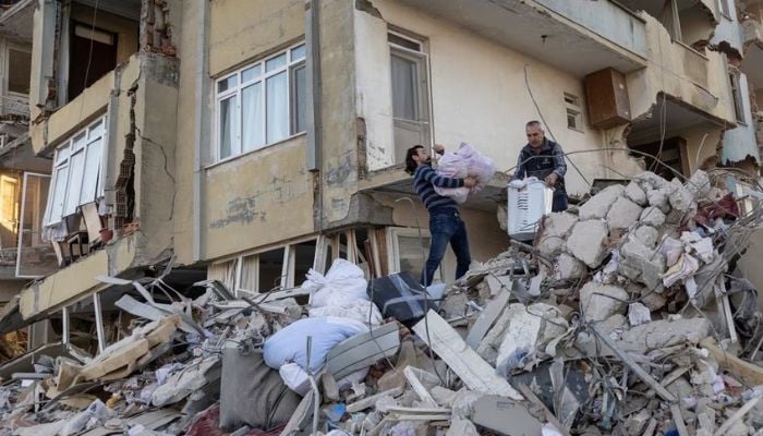 Arsin and his father take belongings out of their destroyed apartment in the aftermath of the deadly earthquake in Antakya, Hatay province, Turkey, February 20, 2023.— Reuters